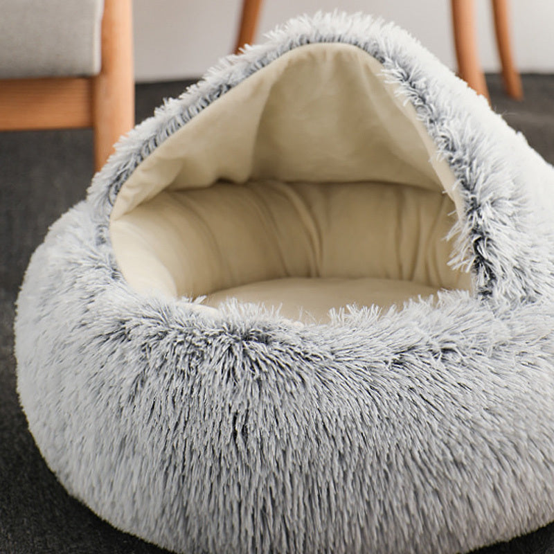 Gray fluffy pet bed with beige interior on a dark surface