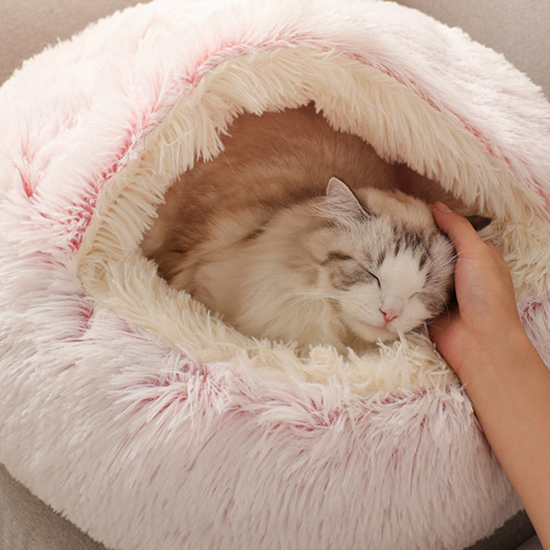 
Cat lying in a fluffy pink pet bed with a hand petting it